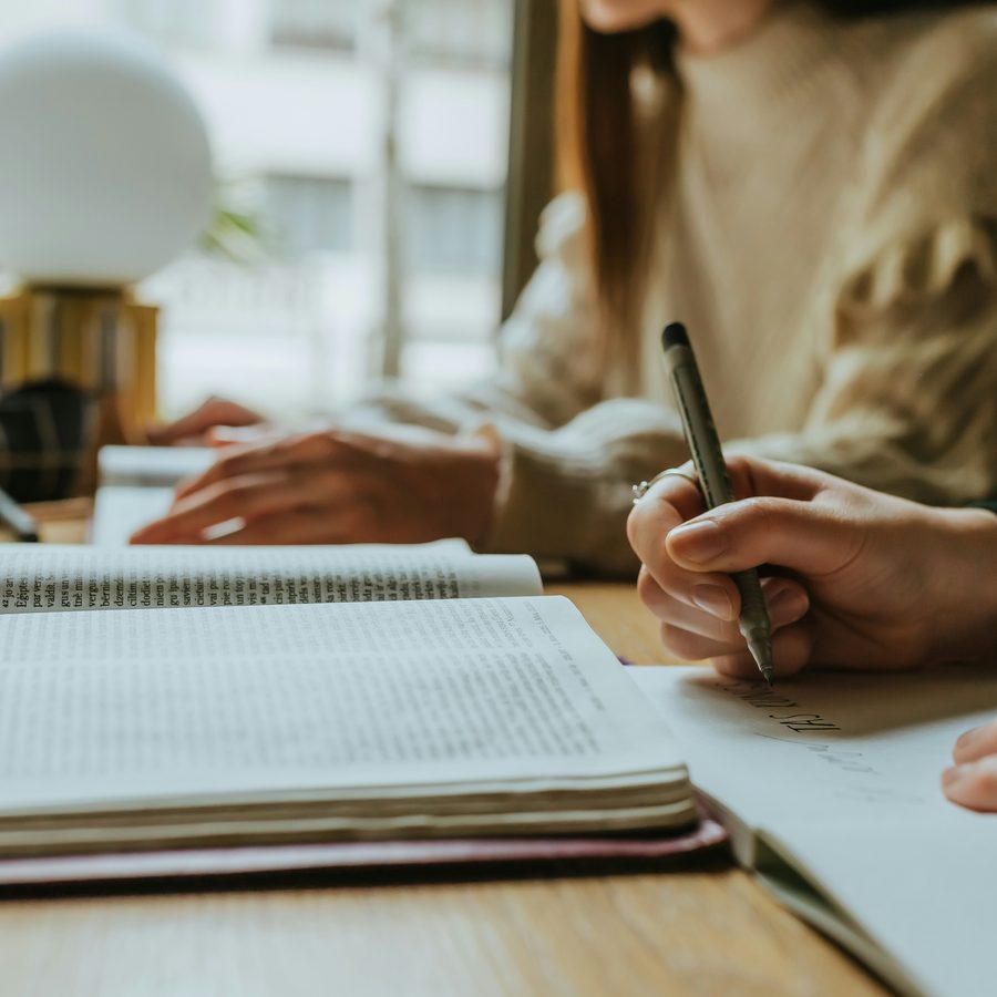 Hands writing notes in an open notebook at a desk