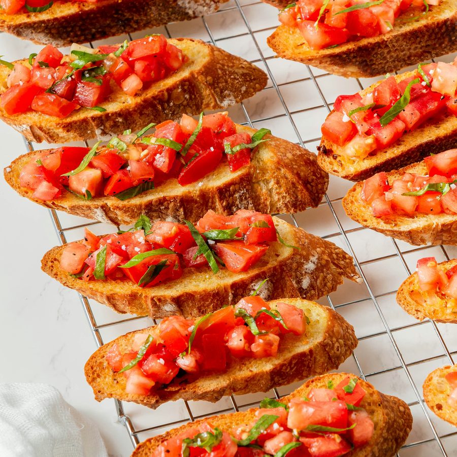 Bruschette topped with tomato, cooling on a rack